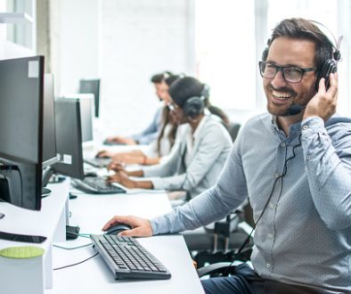 Smiling handsome customer support operator with headset working in call center.